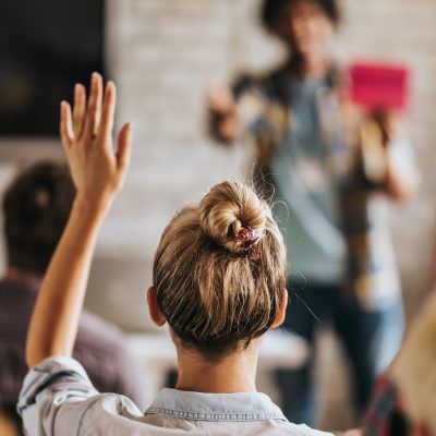 Kvinne sitter på generalforsamling og rekker opp haanden