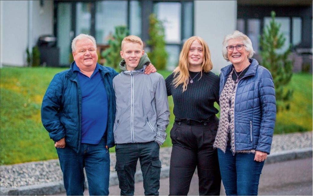 Bestemor og bestefar står sammen med barnebarna utenfor et rekkehus