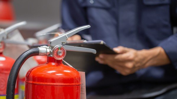 En brannteknisk ekspert gjennomfører sjekk av et brannslukningsapparat.
