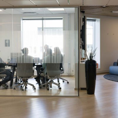 Et møte finner sted i et moderne konferanserom med glassvegger, hvor seks personer sitter rundt et bord og diskuterer muligheter for jobb i BORI, sett utenfra.